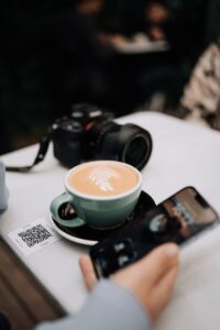 a person taking a picture of a cup of coffee