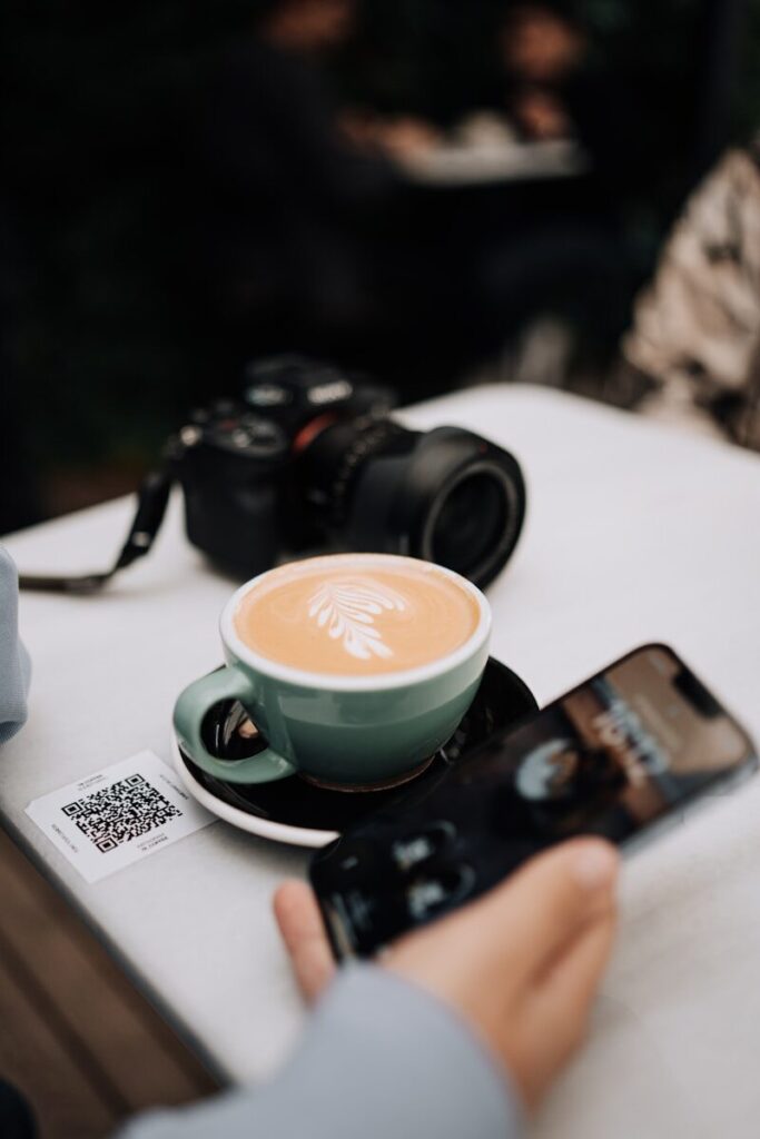 a person taking a picture of a cup of coffee