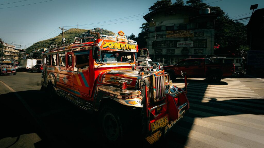 A colorful jeepney drives through a city.