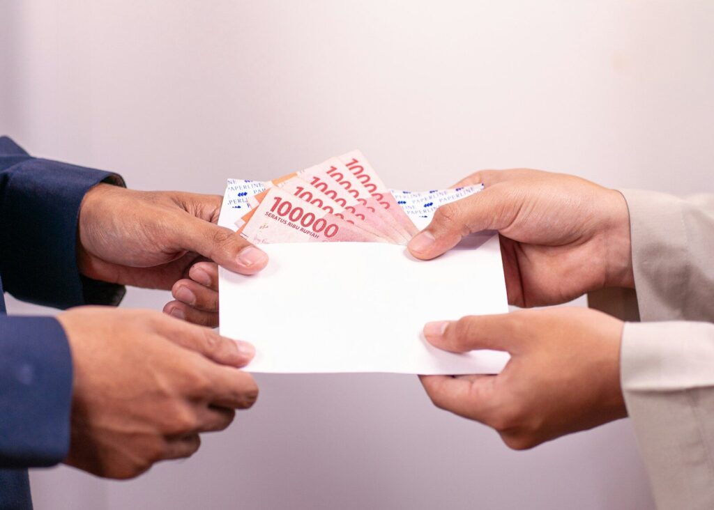 A person is giving money in an envelope.