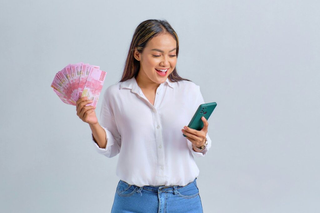 a woman holding a fan of money and a cell phone