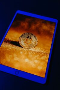 A golden Bitcoin coin displayed digitally on a tablet screen, representing digital currency and blockchain technology.