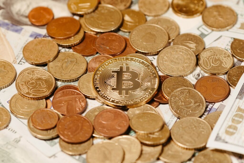 A Bitcoin surrounded by a pile of assorted coins and paper currency. Ideal for financial themes.