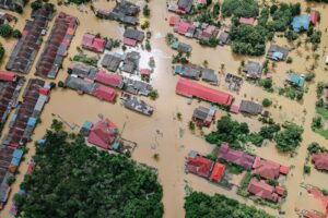 Aerial view of colorful roofs of residential buildings and verdant trees in flooded small village
