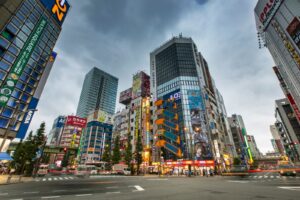Dynamic street scene of Shinjuku, Tokyo with towering skyscrapers and bustling activity.