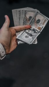 Close-up of a hand holding a stack of US dollar bills, indicating wealth or finance.