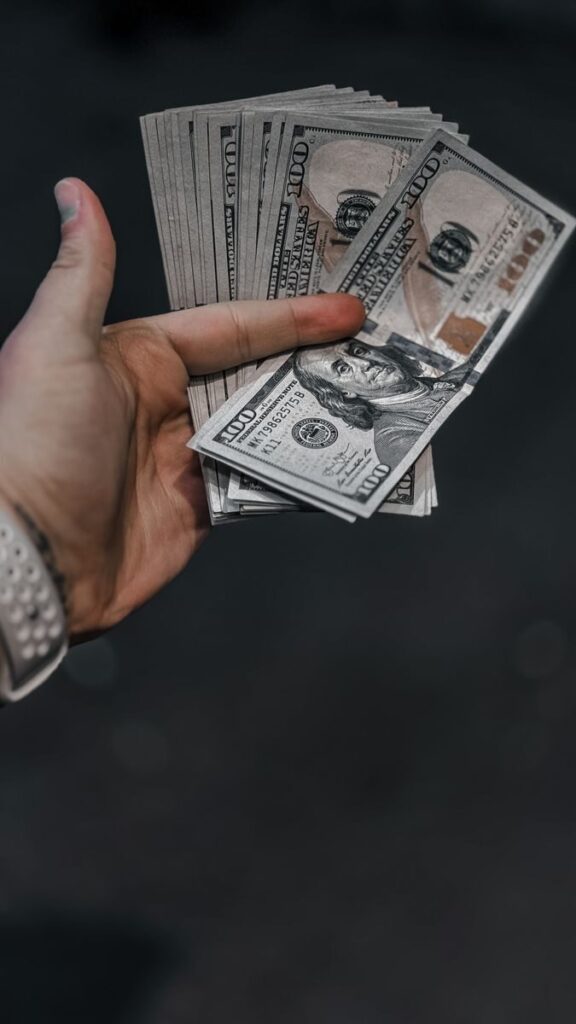 Close-up of a hand holding a stack of US dollar bills, indicating wealth or finance.