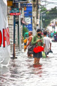 People navigate a flooded street in Malabon, Metro Manila, after heavy rains.