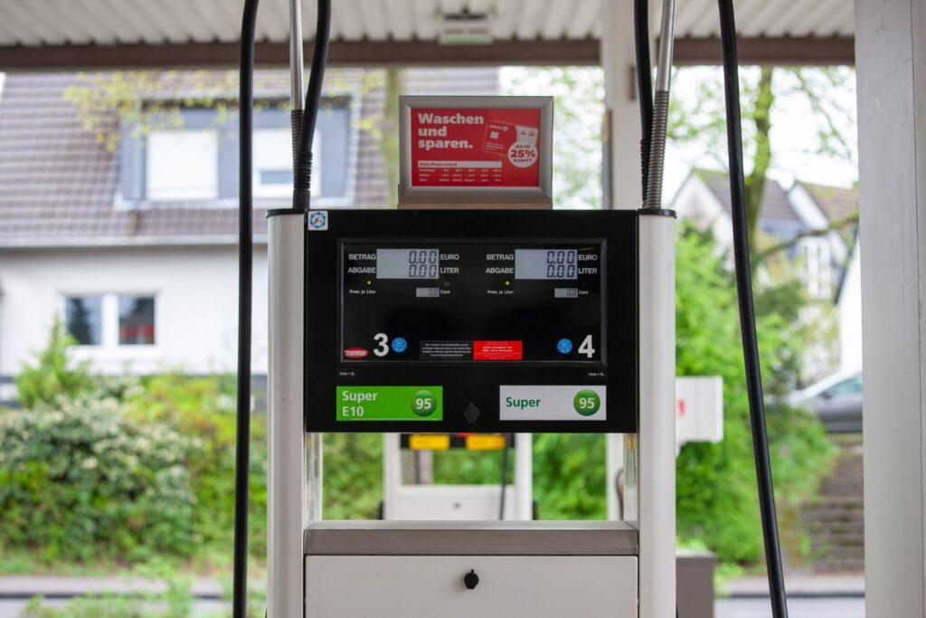 Close-up of a gas pump at a station in Bergisch Gladbach, Germany, with surrounding houses visible.