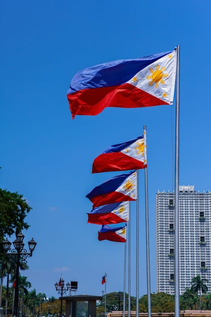 Vibrant Philippine flags waving outdoors with blue sky in Pasay City, NCR, Philippines.