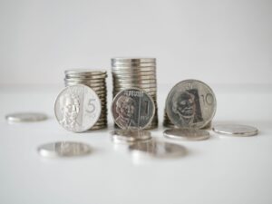 Stacked and scattered Philippine Peso coins in a close-up view on a white surface.